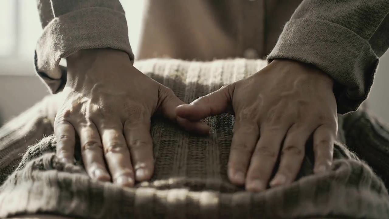 Deux mains qui massent un dos à travers un pull en laine tricoté