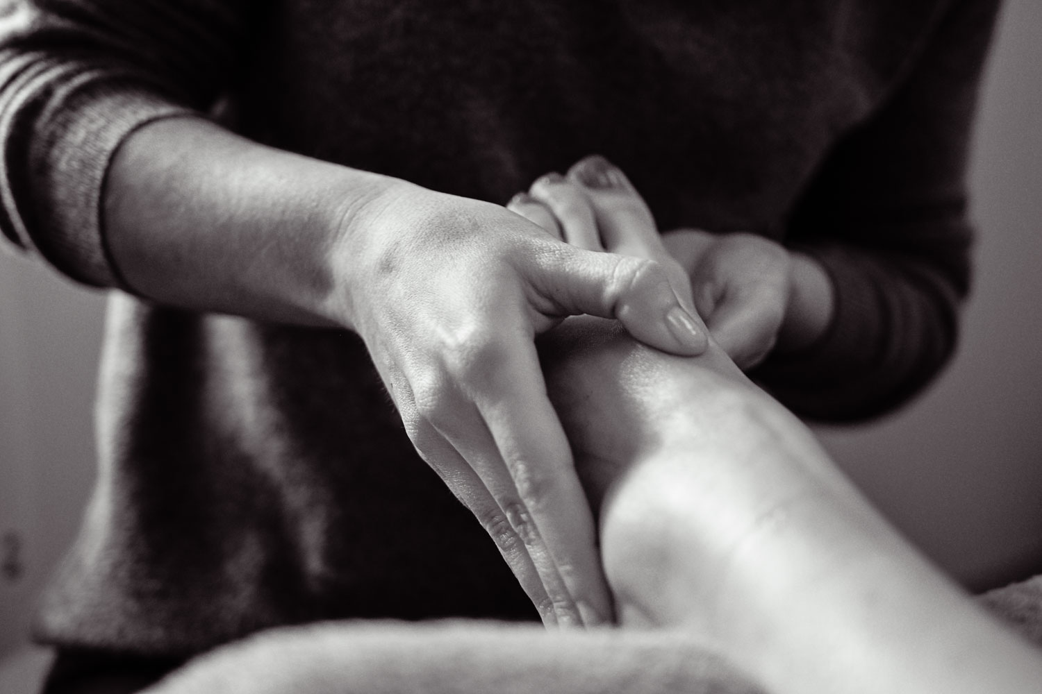 Les mains de Claire exécutent une pression précise sur le poignet d’un patient