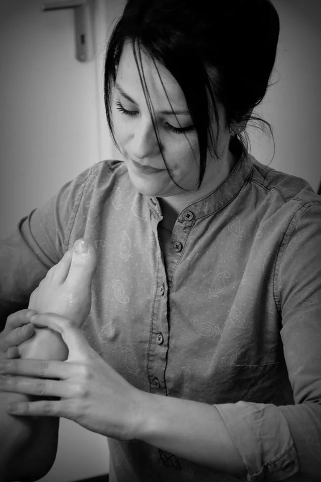 Claire Missol en train de masser un pied, visage légèrement tourné, regard concentré sur le geste