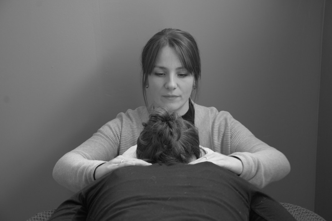 Claire Missol de face, concentrée, en train de masser les épaules et la nuque d’une patiente pendant une séance